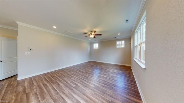 spare room with baseboards, wood finished floors, visible vents, and ornamental molding