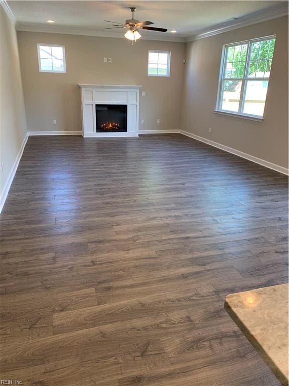 unfurnished living room with plenty of natural light, a warm lit fireplace, and ornamental molding