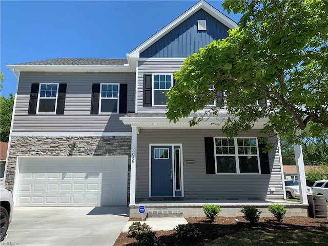 view of front of property featuring stone siding, an attached garage, board and batten siding, and driveway