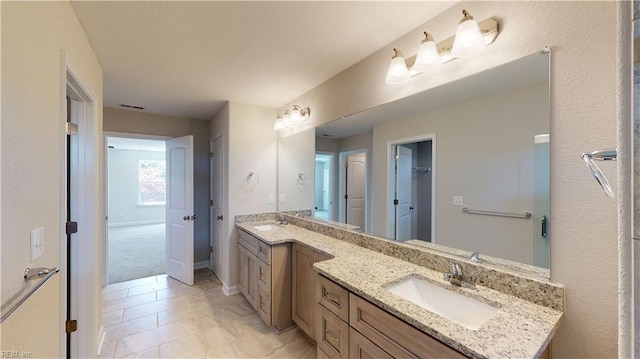 full bathroom with a sink, visible vents, baseboards, and double vanity