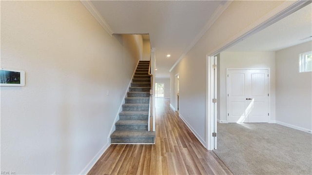 staircase with recessed lighting, wood finished floors, baseboards, and ornamental molding