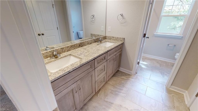 bathroom featuring double vanity, toilet, and a sink