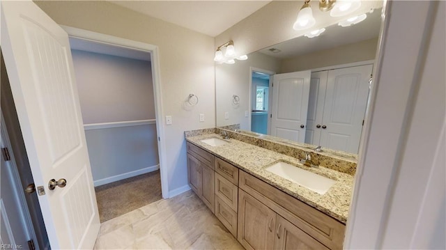 bathroom featuring double vanity, baseboards, and a sink