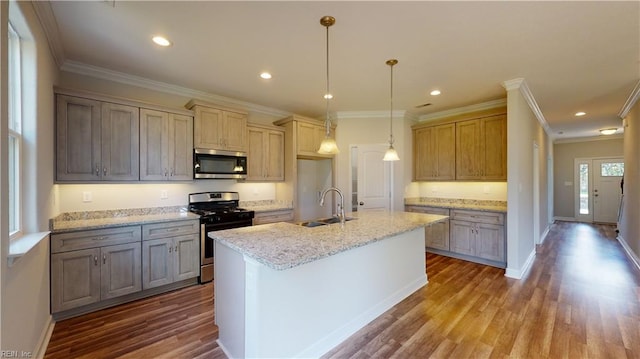 kitchen with a kitchen island with sink, a sink, dark wood-style floors, stainless steel appliances, and crown molding