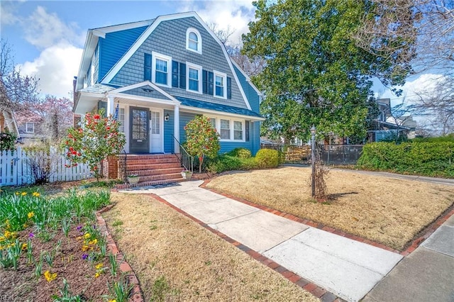 view of front facade with a gambrel roof, a front yard, and fence