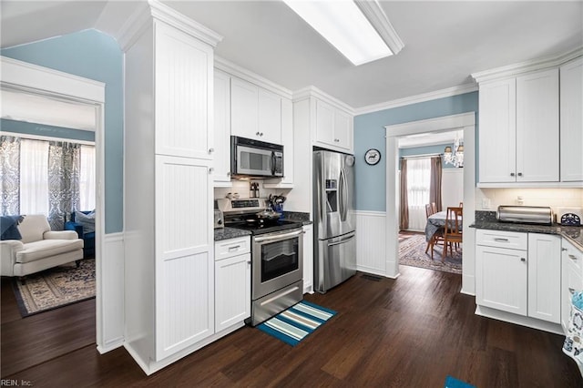 kitchen featuring an inviting chandelier, dark wood-style floors, appliances with stainless steel finishes, and wainscoting