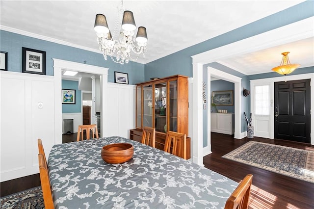 dining space featuring an inviting chandelier, dark wood-style floors, wainscoting, and crown molding