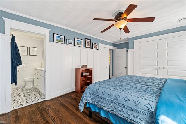 bedroom with visible vents, ceiling fan, a wainscoted wall, ornamental molding, and dark wood-style flooring