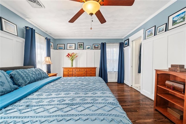 bedroom with dark wood-style floors, visible vents, multiple windows, and a decorative wall