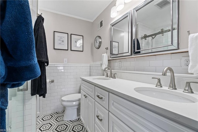 bathroom featuring tile patterned floors, visible vents, toilet, a sink, and tile walls