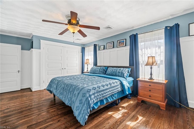 bedroom with a closet, visible vents, crown molding, and wood finished floors