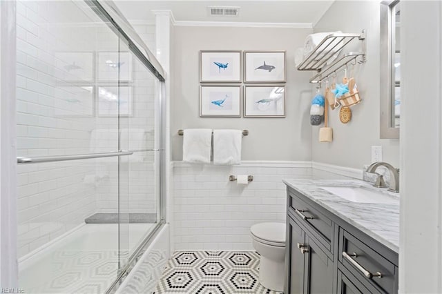 bathroom featuring visible vents, toilet, tile walls, and crown molding