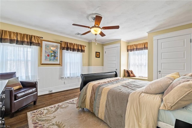 bedroom featuring multiple windows, wood finished floors, and a wainscoted wall