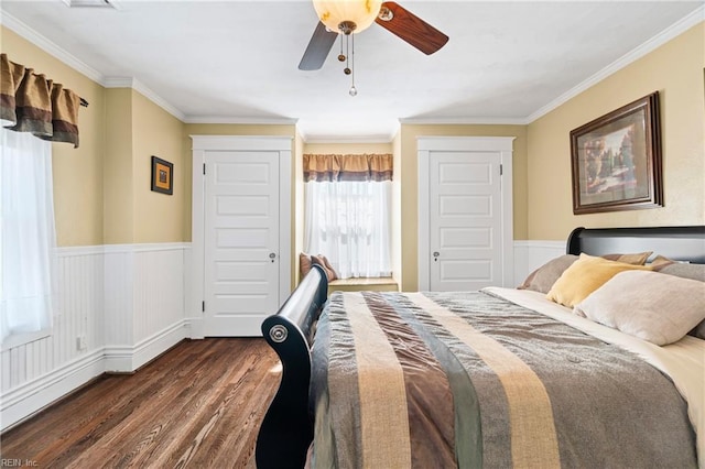 bedroom featuring a ceiling fan, dark wood-type flooring, wainscoting, and crown molding