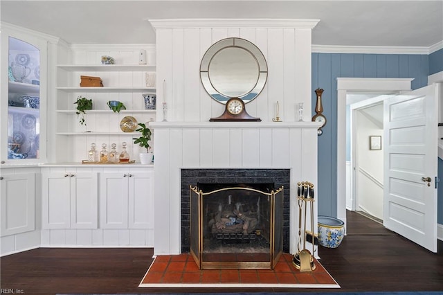 living area with dark wood-style floors, built in features, a fireplace, and crown molding