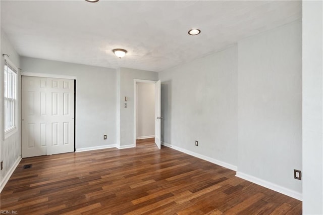 unfurnished bedroom with visible vents, wood finished floors, baseboards, and a closet