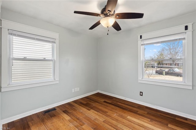 empty room with visible vents, a ceiling fan, baseboards, and wood finished floors