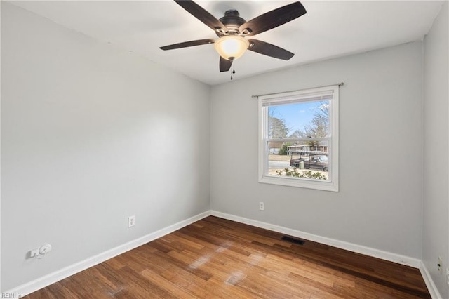 empty room featuring ceiling fan, visible vents, baseboards, and wood finished floors