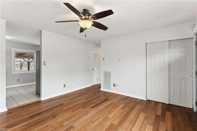 unfurnished bedroom featuring visible vents, baseboards, wood finished floors, a closet, and a ceiling fan