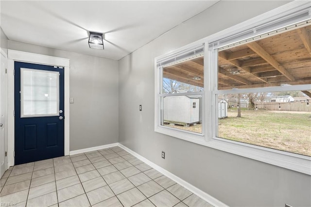 foyer entrance with light tile patterned floors and baseboards