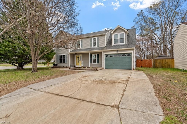 traditional-style house featuring driveway, a front lawn, a garage, and fence