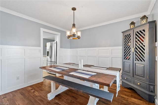 dining area with a decorative wall, a notable chandelier, dark wood-type flooring, and ornamental molding