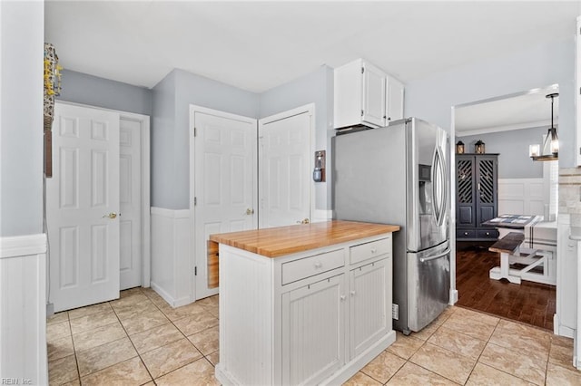 kitchen featuring butcher block countertops, light tile patterned floors, wainscoting, stainless steel refrigerator with ice dispenser, and white cabinets