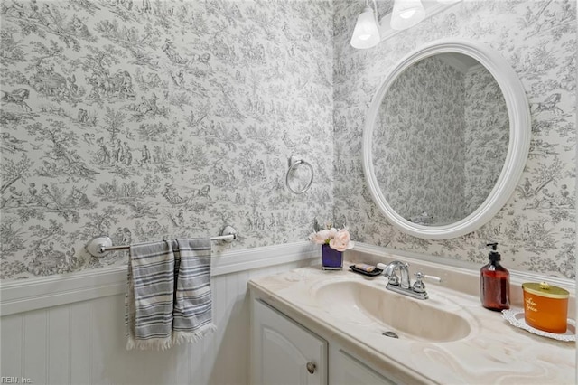 bathroom with wainscoting, wallpapered walls, and vanity