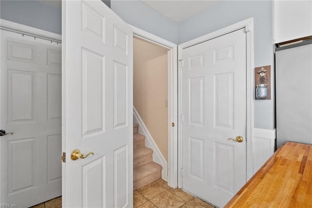 stairway with tile patterned floors and baseboards