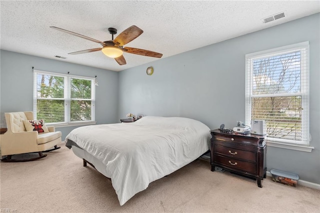 bedroom featuring a textured ceiling, carpet, visible vents, and ceiling fan