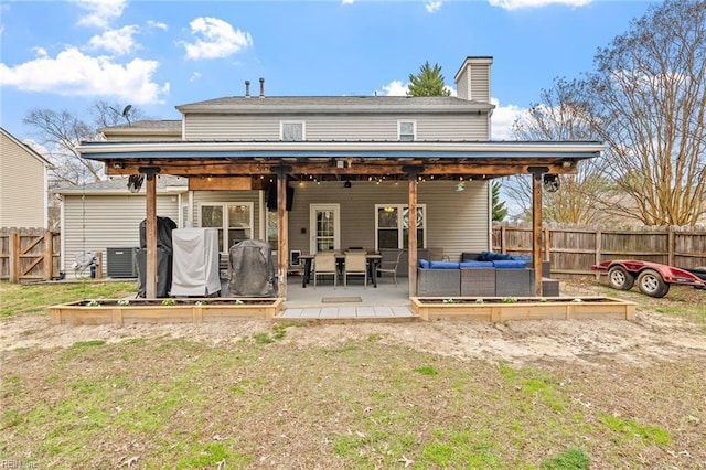 back of property featuring a patio, a chimney, a vegetable garden, and fence