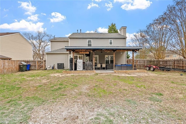 rear view of property featuring central AC unit, a chimney, a yard, a fenced backyard, and a patio