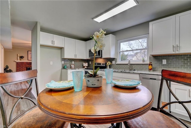 kitchen featuring a sink, decorative backsplash, white cabinetry, and stainless steel appliances