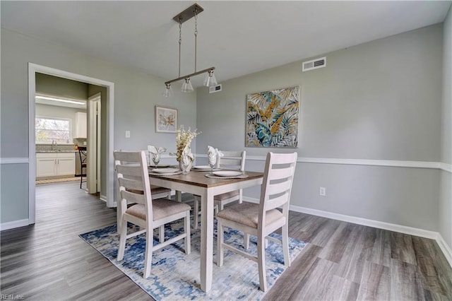 dining area featuring visible vents, baseboards, and wood finished floors