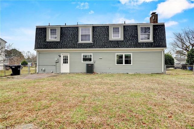 rear view of house featuring a chimney, a lawn, a shingled roof, and fence