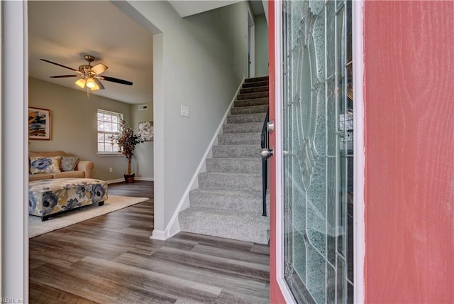 stairway featuring ceiling fan, baseboards, and wood finished floors