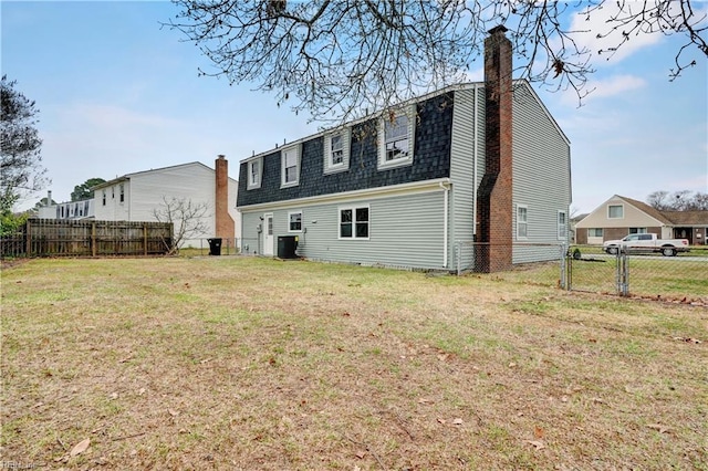 back of property with central AC unit, a gate, a lawn, and fence