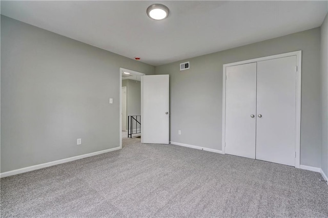 unfurnished bedroom featuring a closet, visible vents, baseboards, and carpet