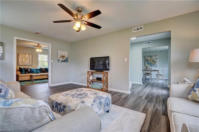 living room featuring visible vents, baseboards, a ceiling fan, and wood finished floors