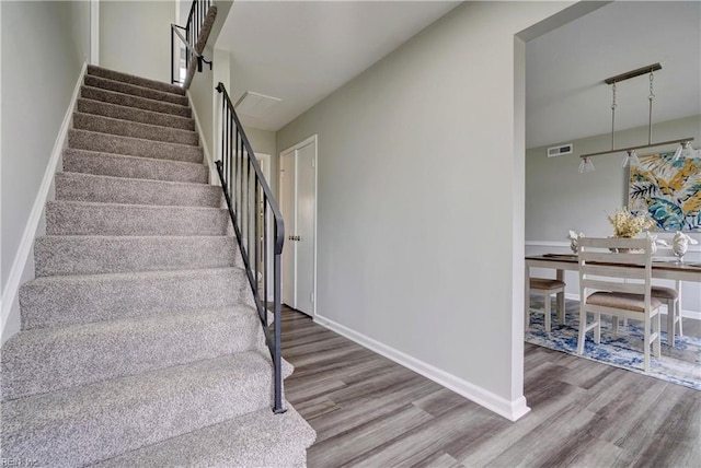 stairs featuring visible vents, baseboards, and wood finished floors