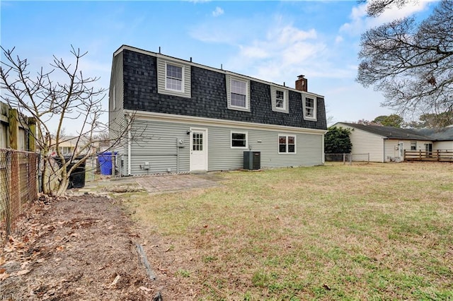 back of house featuring a gambrel roof, a lawn, a fenced backyard, and a shingled roof