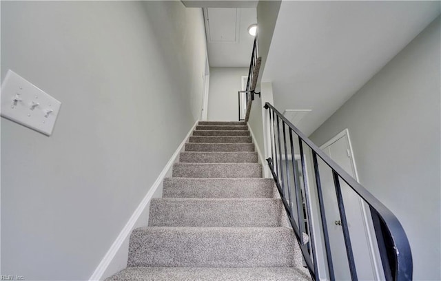 staircase featuring attic access and baseboards