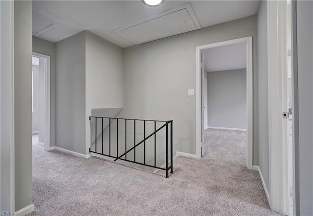 hall featuring baseboards, an upstairs landing, attic access, and carpet flooring