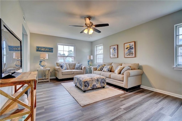 living area featuring baseboards, wood finished floors, and ceiling fan