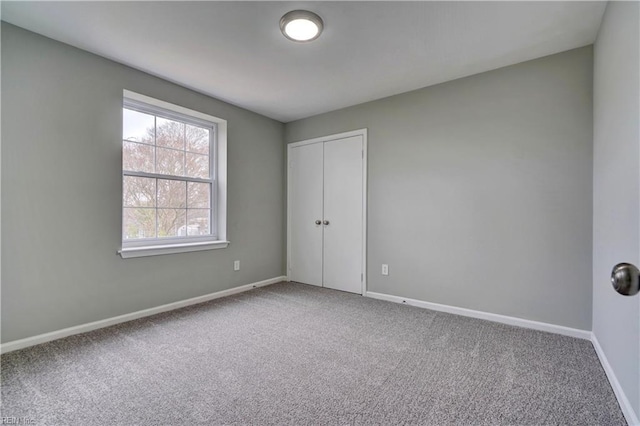 unfurnished bedroom with a closet, baseboards, and carpet flooring