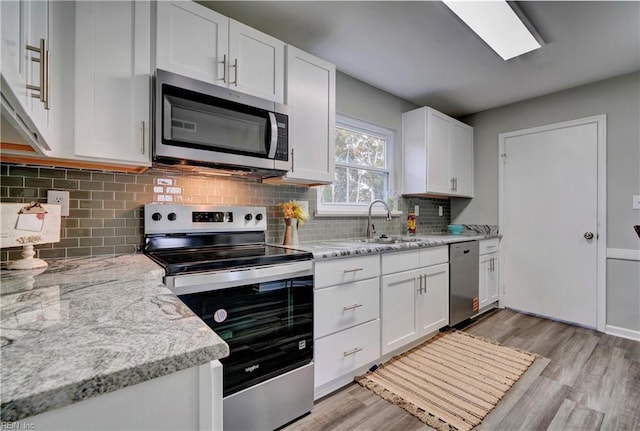 kitchen with white cabinets, appliances with stainless steel finishes, light wood-type flooring, and a sink