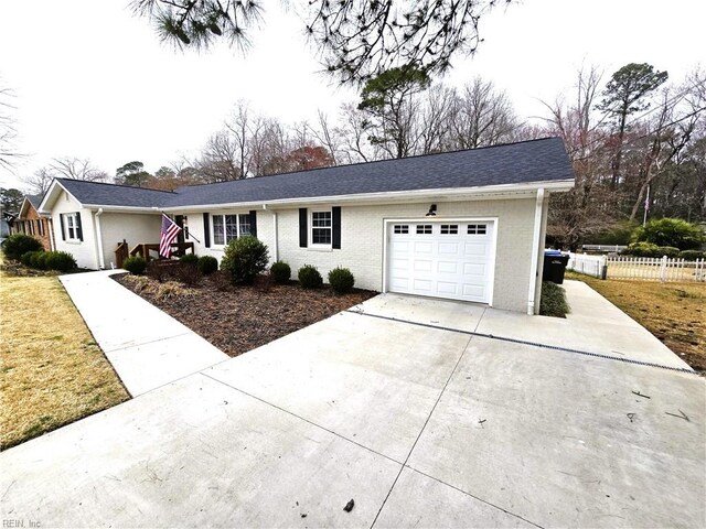 ranch-style home with driveway, brick siding, an attached garage, and fence