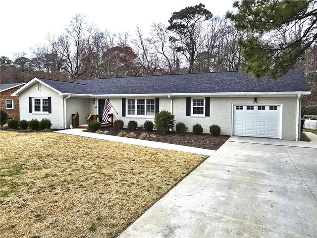 ranch-style home with driveway, brick siding, roof with shingles, and an attached garage