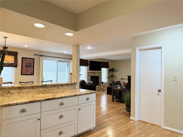 kitchen with light stone counters, recessed lighting, light wood-style flooring, a fireplace, and white cabinetry