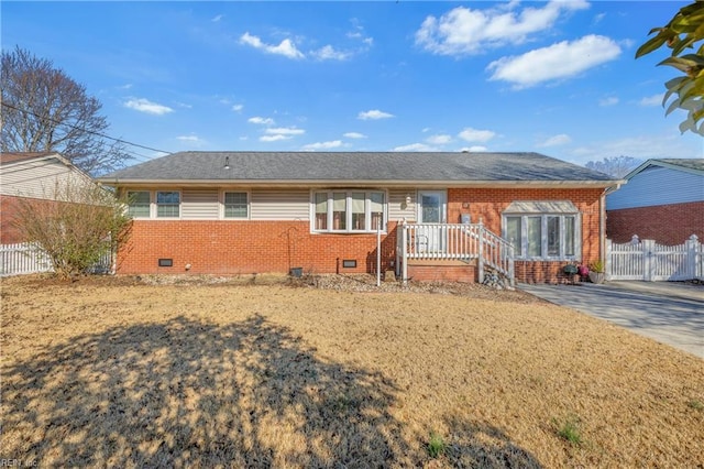 view of front of home with crawl space, brick siding, and fence